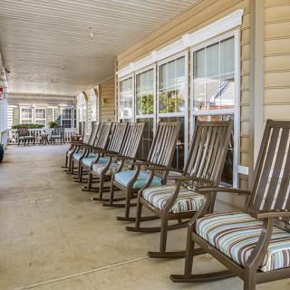 A row of rocking chairs on a porch gives a cozy and relaxing outdoor seating area.