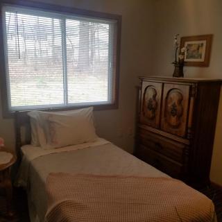 A cozy bedroom with a single bed and wooden furniture by the window.