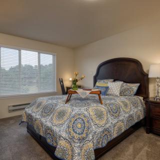 A cozy bedroom with a large bed, decorative pillows, and bedside lamps.
