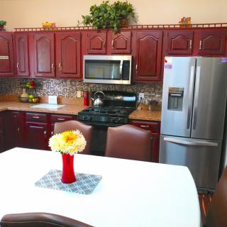 A modern kitchen with wooden cabinets, stainless steel appliances, and a dining table decorated with flowers.