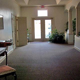 A quiet hallway with carpeted flooring, featuring doors at the end and minimal furnishings.