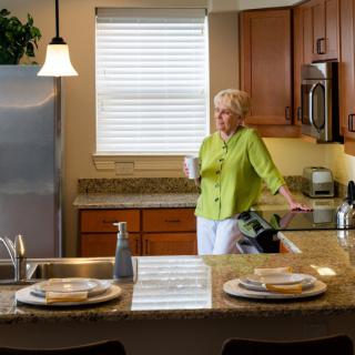 A woman enjoying a drink in a modern kitchen.