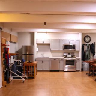 A modern apartment kitchen with stainless steel appliances and wooden flooring.