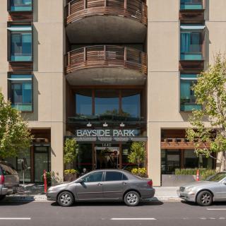 An urban building with a prominent entrance and parked cars along the city street.