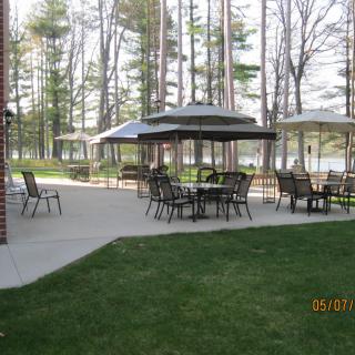 Outdoor patio area with tables, chairs, and gazebos surrounded by trees.