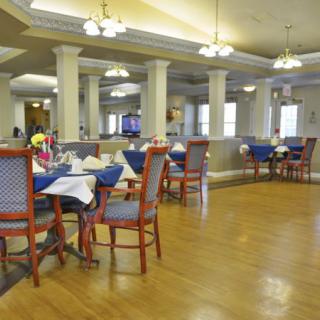 Spacious dining area with neatly arranged tables and chairs, featuring elegant lighting.