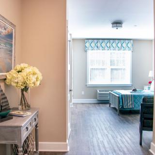 A bright and elegantly decorated living room with a table adorned with flowers and large window curtains.