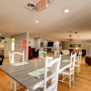 A spacious dining area with a wooden table and chairs, featuring an open kitchen layout.