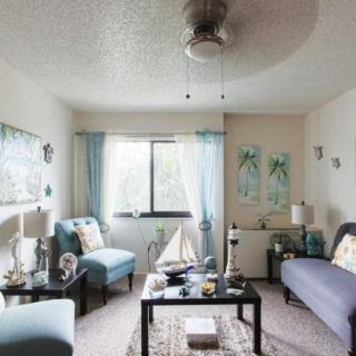 A cozy living room with modern furniture and decor, featuring a sofa, chairs, a coffee table, and artwork on the walls.