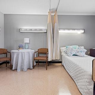 A serene hospital room featuring a bed, chairs, and a small table, designed for patient comfort.