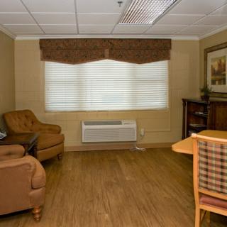 A cozy living room featuring comfortable seating, decorative elements, and a window with blinds.