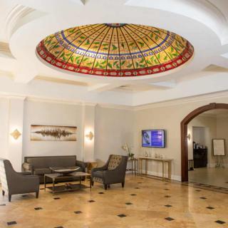 A spacious lobby featuring a stained glass dome ceiling and elegant seating arrangement.