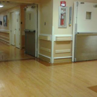A quiet hospital hallway featuring wooden flooring and closed doors.