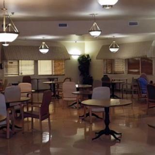 A quiet dining area with several tables and chairs under ceiling lights.
