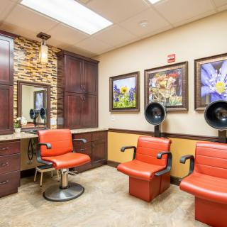 A modern salon interior featuring red chairs, hair dryers, and wall art.