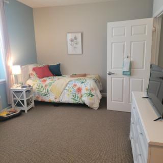 A cozy bedroom with a floral bedspread, side table, and dresser.