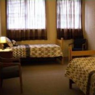 A cozy dorm room with two beds and simple furnishings.