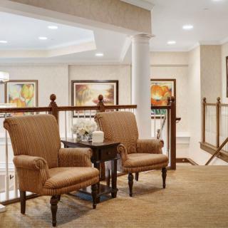 A cozy lobby area featuring two upholstered chairs, a side table, and decorative artwork on the walls.