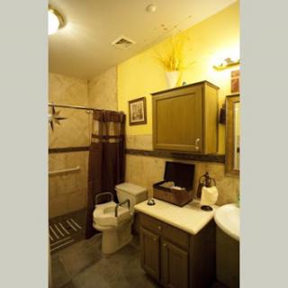 A cozy bathroom featuring a shower, toilet, and wooden cabinets with a warm yellow color scheme.