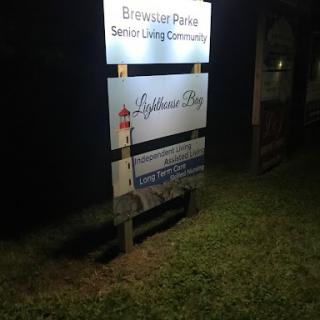Sign for a senior living community named Lighthouse Bay, illuminated at night.