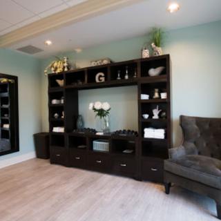 A cozy living room with a large dark wooden bookshelf and an armchair, decorated with plants and ornaments.