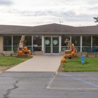 A building entrance decorated with pumpkins and autumn-themed items.
