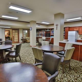 A communal dining and kitchen area with tables, chairs, and kitchen appliances.