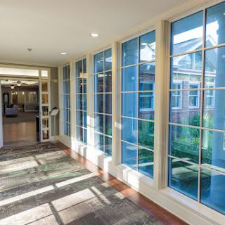 A well-lit hallway with large windows allowing natural light to illuminate the space.