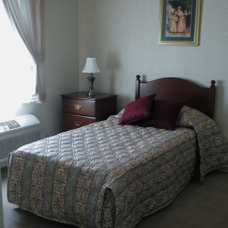 A cozy bedroom with a single bed, nightstand, and window with curtains.