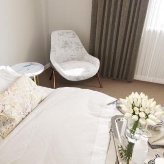 A modern, minimalist bedroom featuring a comfortable bed, stylish chair, and elegant floral decor.