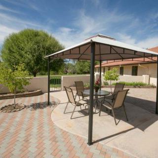 A serene backyard patio featuring a gazebo with outdoor furniture, surrounded by lush landscaping.
