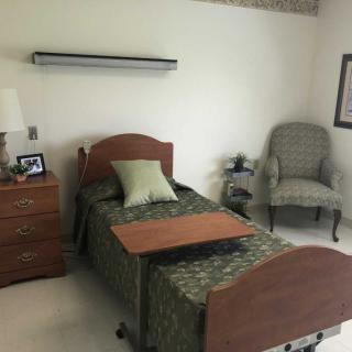 A cozy and minimalist bedroom with a single bed, bedside table, and armchair.