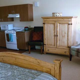 A cozy studio apartment with a combined kitchen and bedroom area featuring wooden furniture.
