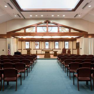 An interior view of a synagogue featuring rows of seating and a raised pulpit area.