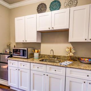 A cozy kitchen with white cabinets, featuring a microwave, oven, and decorative plates above the countertop.