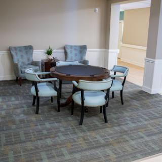 A cozy seating arrangement featuring a round table and four chairs, complemented by two armchairs in a welcoming interior space.