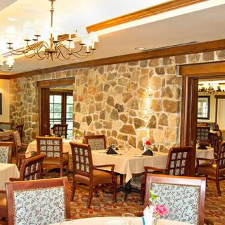 A cozy restaurant dining area featuring stone walls and wooden furniture.