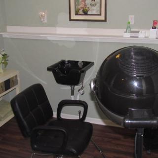 A hair salon interior with a chair, hair dryer, and sink.