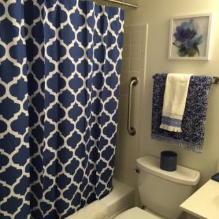 A bathroom with a blue and white patterned shower curtain and matching towels.