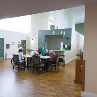 Elderly individuals gathered around a table in a communal seating area.