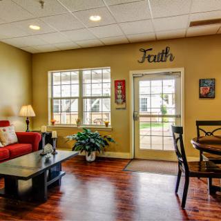 A cozy living room setup featuring a red couch, wooden table, and large windows that invite natural light.