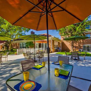A sunny patio with tables set for outdoor dining in a garden setting.