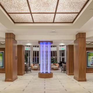 A spacious and modern lobby featuring wooden columns and a central lighting fixture.