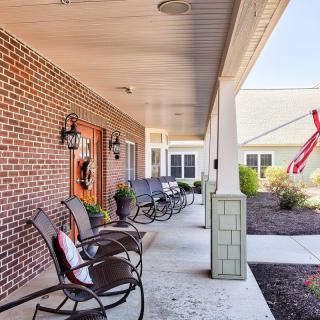 A cozy porch with chairs lined up against a brick wall, alongside a well-maintained patio area.