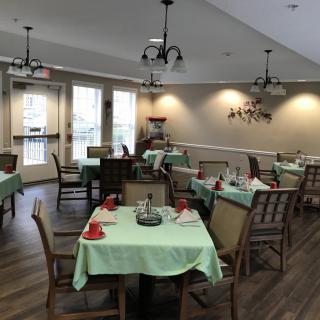 A cozy dining room with neatly arranged tables and chairs, featuring soft lighting and elegant decor.