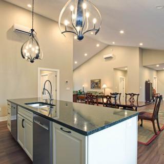 A modern kitchen with an island and open floor plan, featuring elegant chandeliers and a dining area.