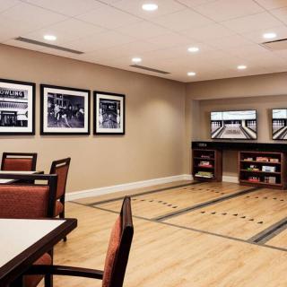 A modern game room with a shuffleboard table and seating area.