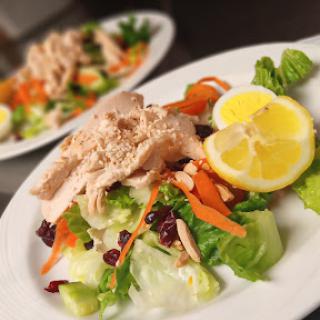 A fresh salad topped with tender chicken, garnished with lemon slices and colorful vegetables.