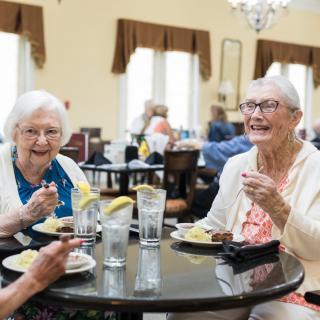 A group of elderly women enjoying a meal together in a dining setting.