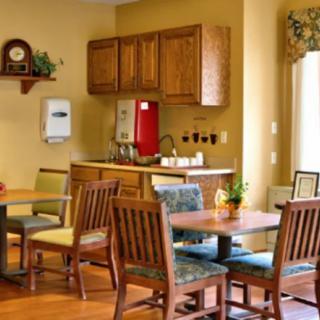 A cozy dining area with wooden tables and chairs, adjacent to a kitchen space.